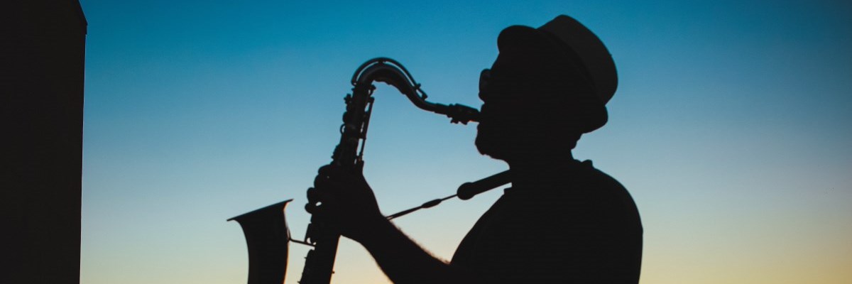 Silhouette of saxophone player with sunset in background