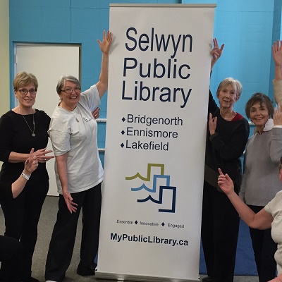Group of adults around library banner