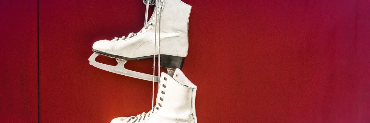 Pair of Figure Skates Hanging from Red Wall