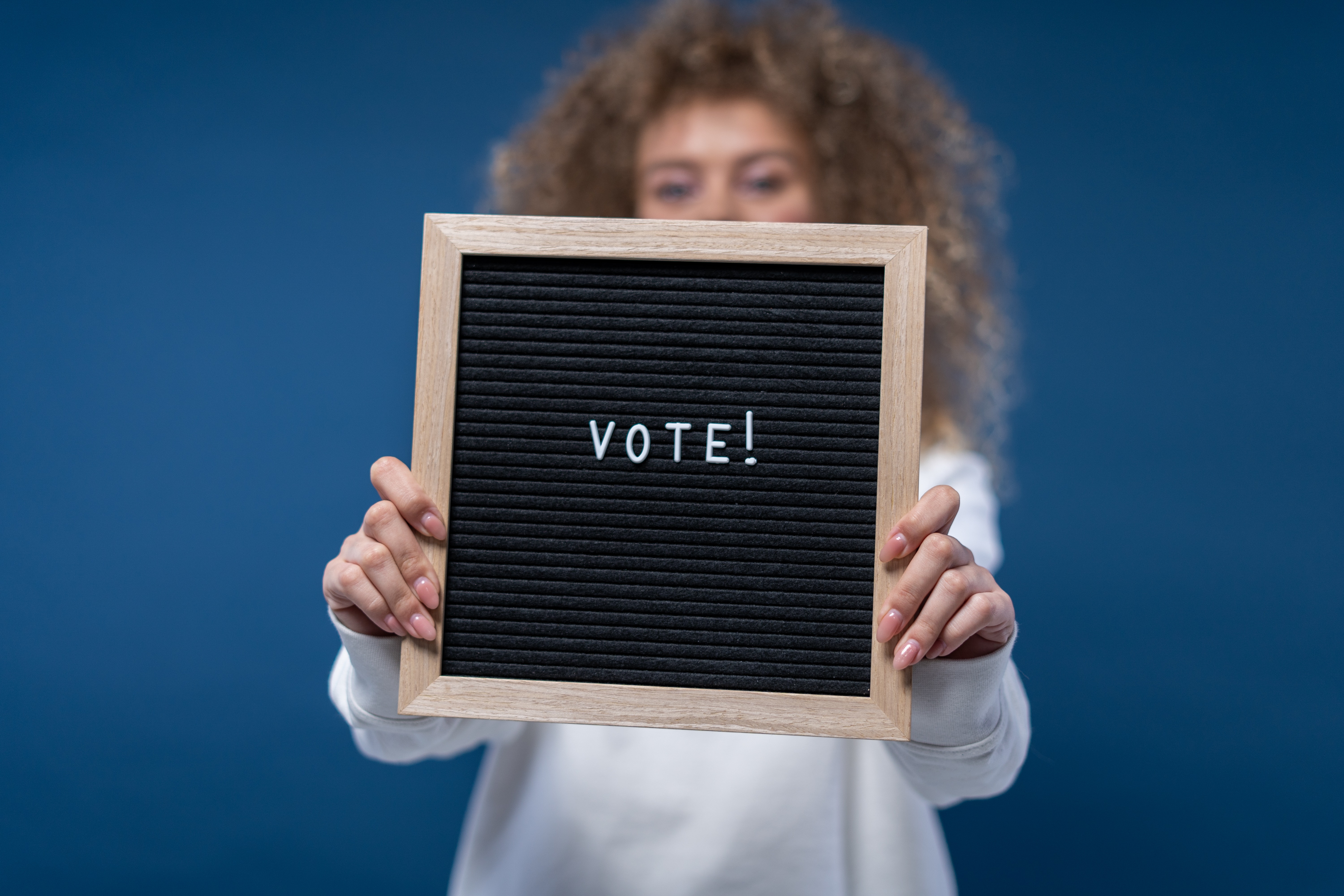 Female holding up a sign that says vote